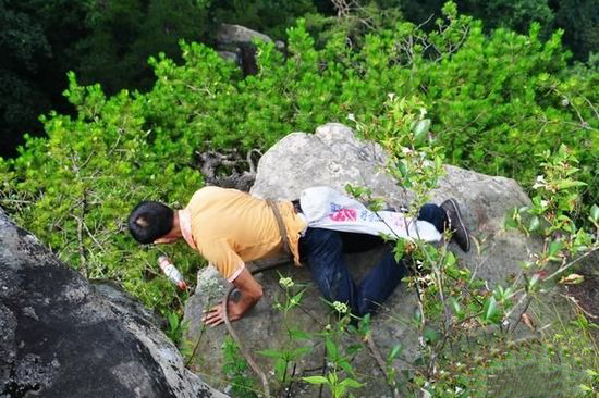  the local cleaner were picking up the garbage in the sheer cliffs which stands in the tourism attractions named Huang Village in Zhangjiajie.