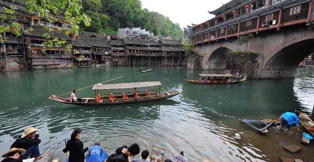 Tourists travel by boats at the Fenghuang ancient town, in Xiangxi Tujia-Miao Autonomous Prefecture of central China